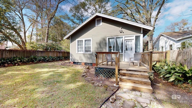 rear view of property featuring a deck, a yard, and a fenced backyard