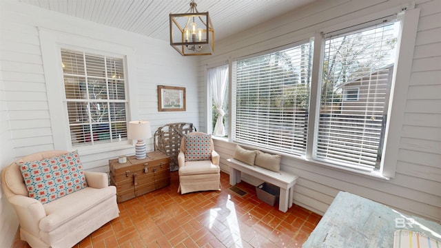 sitting room with wooden walls, a notable chandelier, visible vents, and brick floor