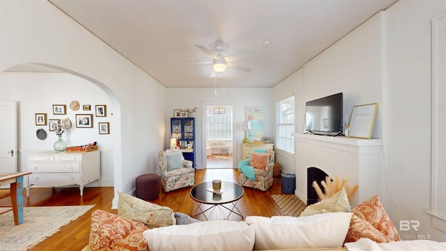 living room featuring arched walkways, a ceiling fan, and wood finished floors