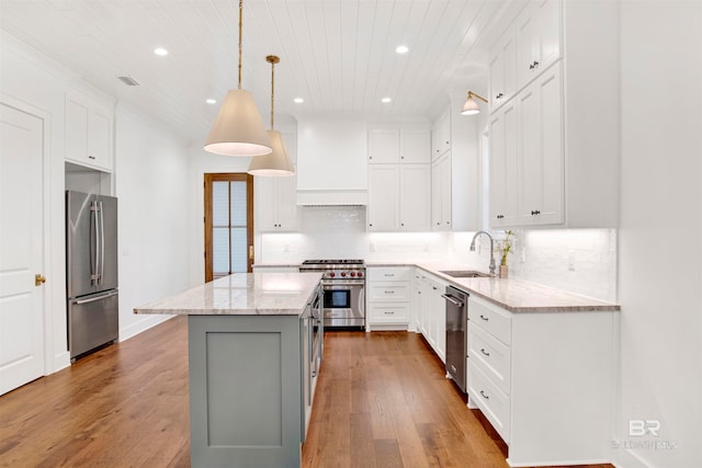 kitchen with appliances with stainless steel finishes, hardwood / wood-style floors, tasteful backsplash, sink, and a center island