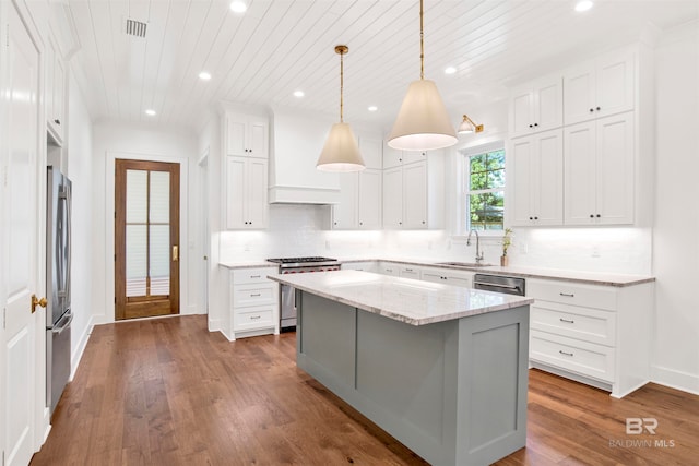 kitchen with hardwood / wood-style floors, backsplash, sink, appliances with stainless steel finishes, and hanging light fixtures