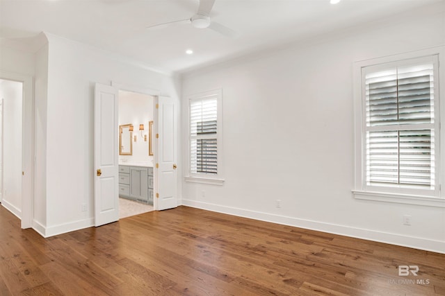 unfurnished bedroom with ceiling fan, ensuite bath, and hardwood / wood-style floors