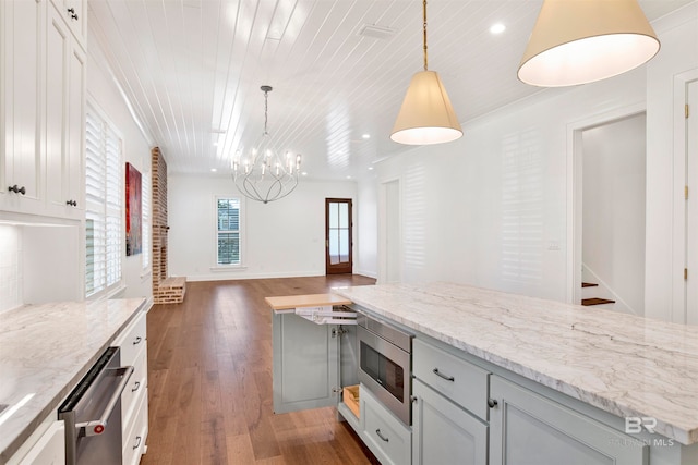 kitchen featuring a notable chandelier, dark hardwood / wood-style flooring, appliances with stainless steel finishes, light stone countertops, and decorative light fixtures