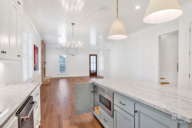 kitchen with pendant lighting, a chandelier, light stone countertops, hardwood / wood-style flooring, and stainless steel appliances