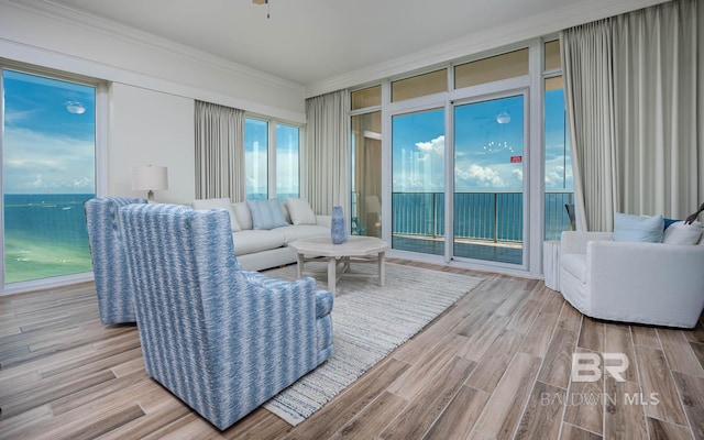 living room with ceiling fan, a water view, and crown molding