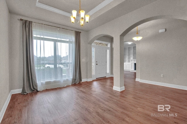 entrance foyer with hardwood / wood-style floors, a tray ceiling, an inviting chandelier, and a textured ceiling