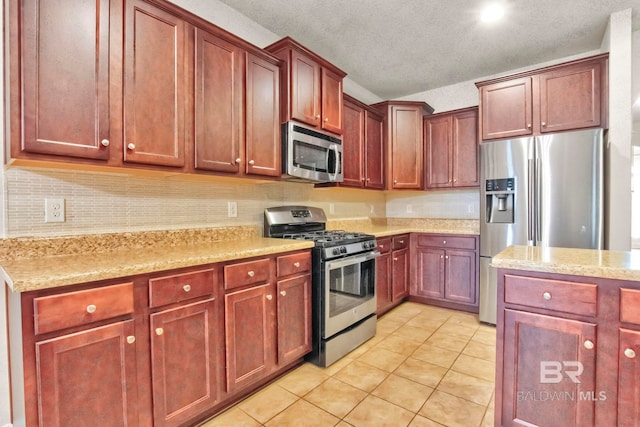 kitchen with a textured ceiling, stainless steel appliances, light stone countertops, and light tile patterned flooring