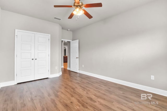 unfurnished bedroom with hardwood / wood-style floors, ceiling fan, and a closet