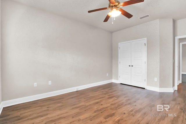 unfurnished bedroom with ceiling fan, a closet, and dark hardwood / wood-style flooring