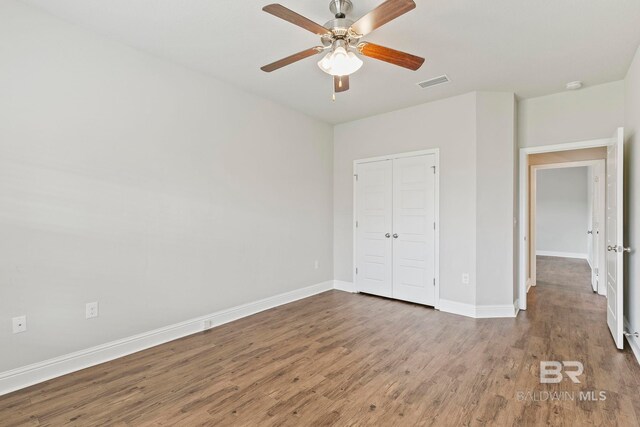 unfurnished bedroom with ceiling fan, a closet, and wood-type flooring