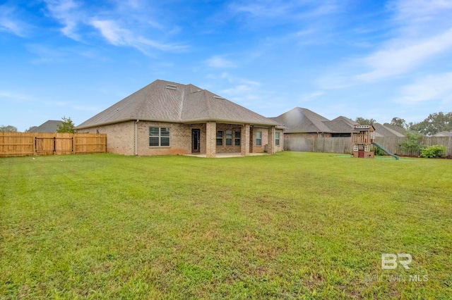 rear view of property featuring a yard and a playground