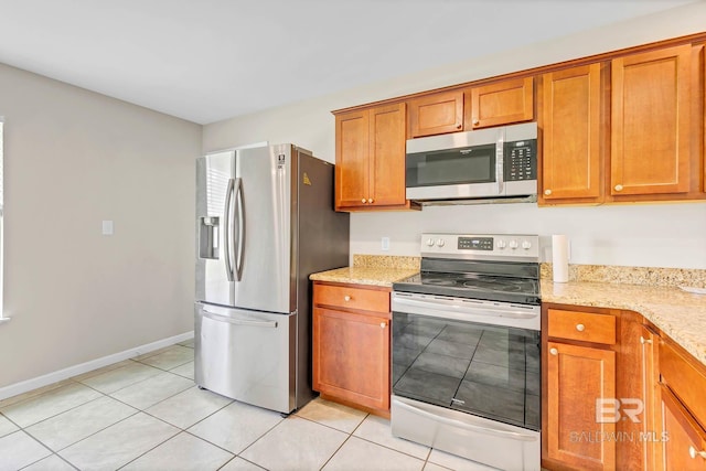15030 Marem Dr, Foley, AL 36535 - kitchen featuring appliances with stainless steel finishes, brown cabinetry, light tile patterned flooring, and light stone counters