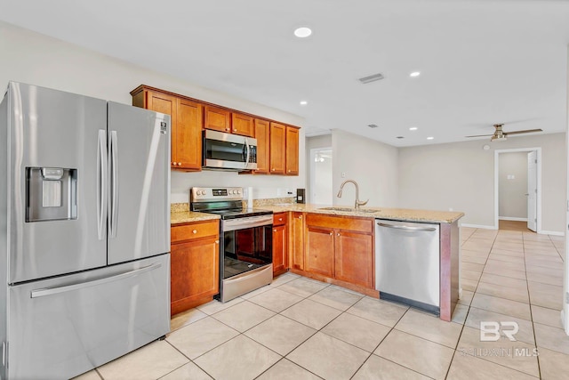 15030 Marem Dr, Foley, AL 36535 - kitchen with stainless steel appliances, a peninsula, brown cabinets, light stone counters, and light tile patterned floors