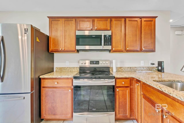 15030 Marem Dr, Foley, AL 36535 - kitchen with appliances with stainless steel finishes, light stone counters, light tile patterned floors, and brown cabinets
