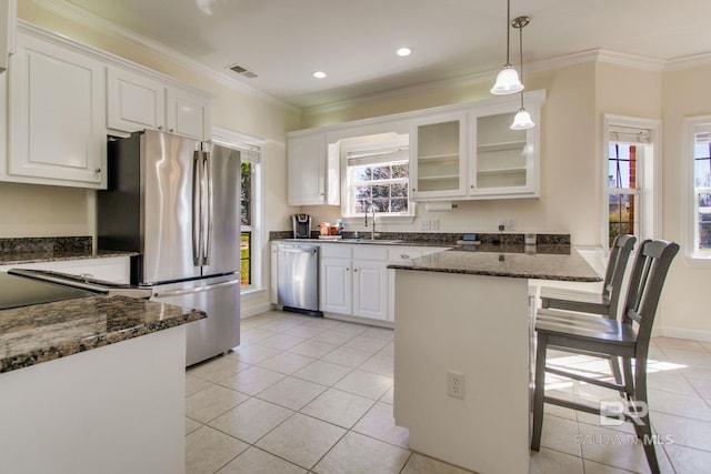 kitchen featuring a breakfast bar area, dark stone counters, stainless steel appliances, and white cabinets