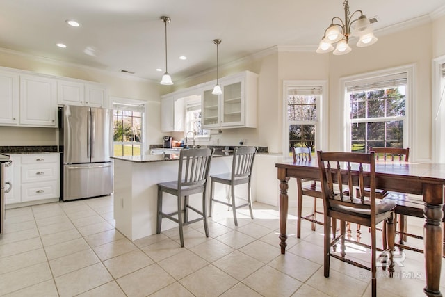 kitchen featuring a breakfast bar, white cabinetry, pendant lighting, and stainless steel refrigerator