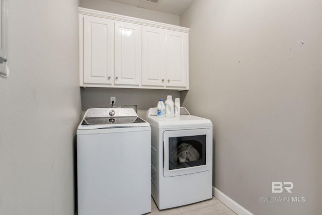 clothes washing area with cabinets and washing machine and dryer