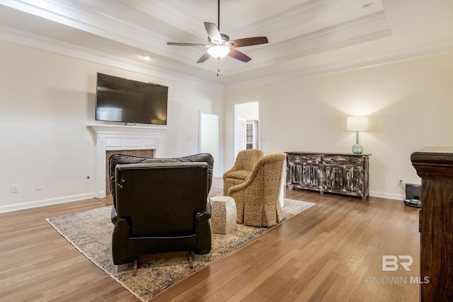 living room featuring a tray ceiling, light hardwood / wood-style flooring, and ornamental molding