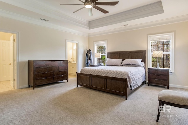 carpeted bedroom featuring a tray ceiling, ornamental molding, ceiling fan, and ensuite bathroom