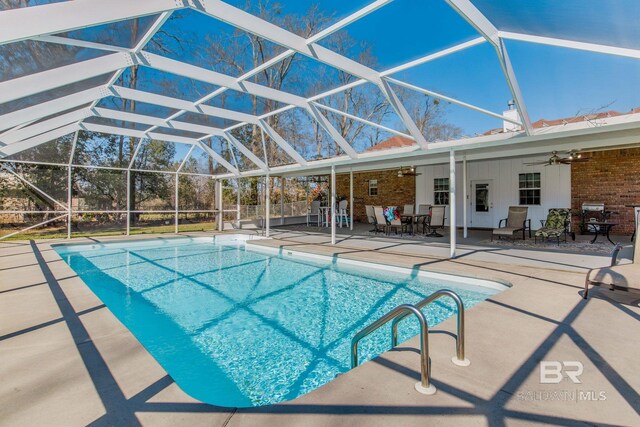 view of swimming pool featuring ceiling fan, a lanai, and a patio