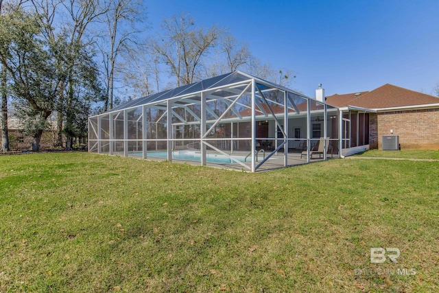rear view of house featuring a patio, central AC unit, a yard, and a lanai
