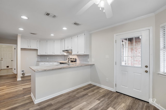 kitchen with kitchen peninsula, crown molding, hardwood / wood-style floors, and white cabinets