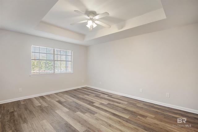 unfurnished room featuring ceiling fan, a raised ceiling, and wood-type flooring