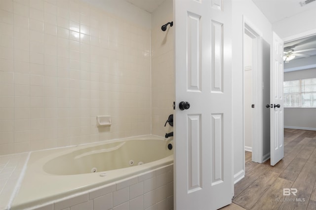 bathroom with ceiling fan, hardwood / wood-style floors, and tiled shower / bath