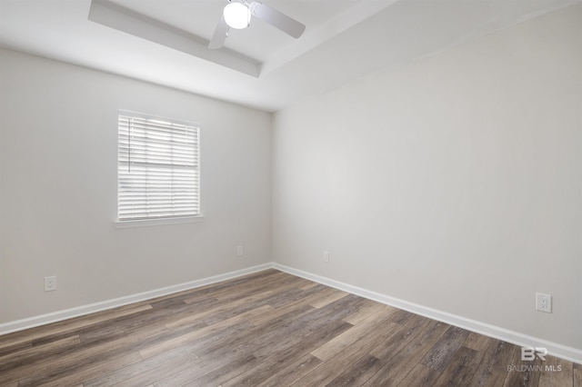 empty room featuring hardwood / wood-style flooring, ceiling fan, and a raised ceiling