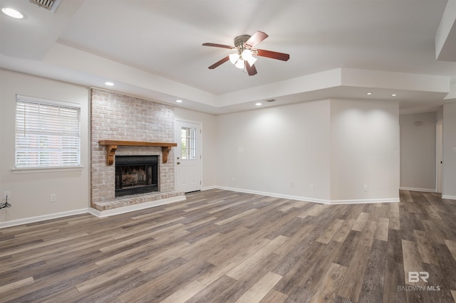 unfurnished living room with a fireplace, ceiling fan, hardwood / wood-style floors, and a healthy amount of sunlight