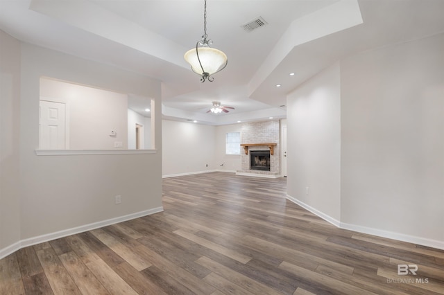 unfurnished living room featuring hardwood / wood-style floors, ceiling fan, and a brick fireplace