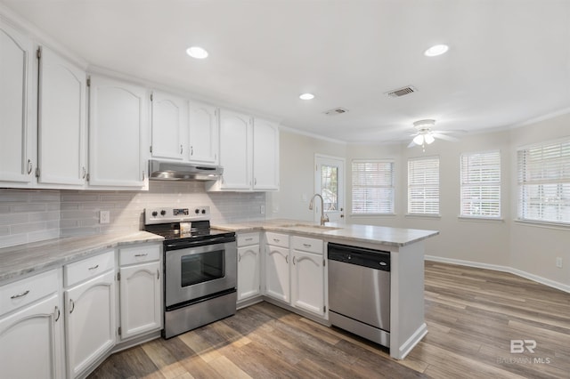 kitchen with sink, white cabinetry, light hardwood / wood-style floors, kitchen peninsula, and stainless steel appliances