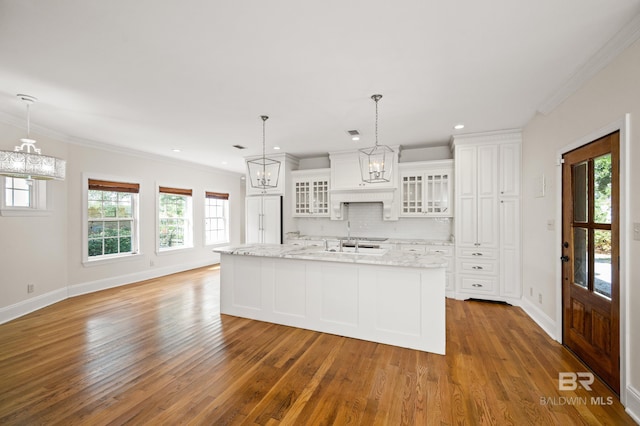 kitchen featuring white cabinets, an island with sink, decorative light fixtures, and dark hardwood / wood-style floors