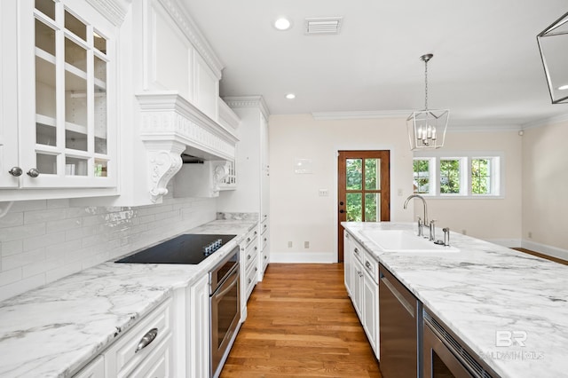 kitchen with white cabinets, appliances with stainless steel finishes, light wood-type flooring, and sink