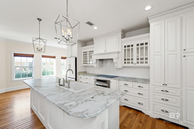 kitchen with white cabinetry, a center island with sink, and sink