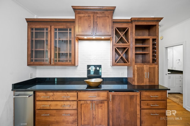 kitchen featuring dark stone counters, wood-type flooring, backsplash, and crown molding