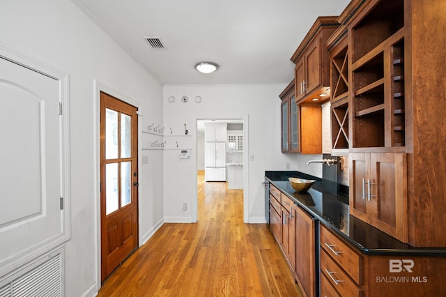 kitchen with wood-type flooring, dark stone countertops, crown molding, and sink