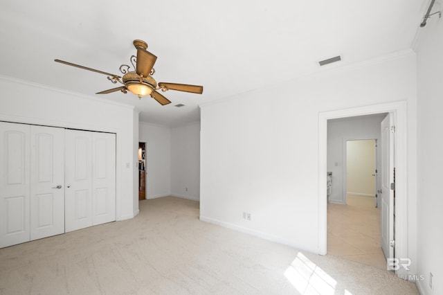 unfurnished bedroom with crown molding, light carpet, ceiling fan, and a closet