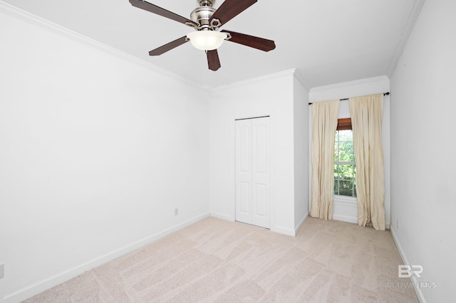 unfurnished bedroom featuring ceiling fan, light colored carpet, a closet, and ornamental molding