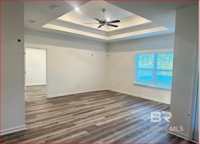 unfurnished room featuring ceiling fan, dark hardwood / wood-style flooring, a raised ceiling, and ornamental molding