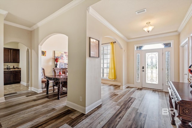 foyer featuring ornamental molding and light wood-type flooring