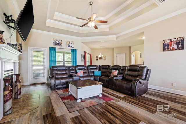 living room with dark wood-type flooring, ornamental molding, and a tray ceiling