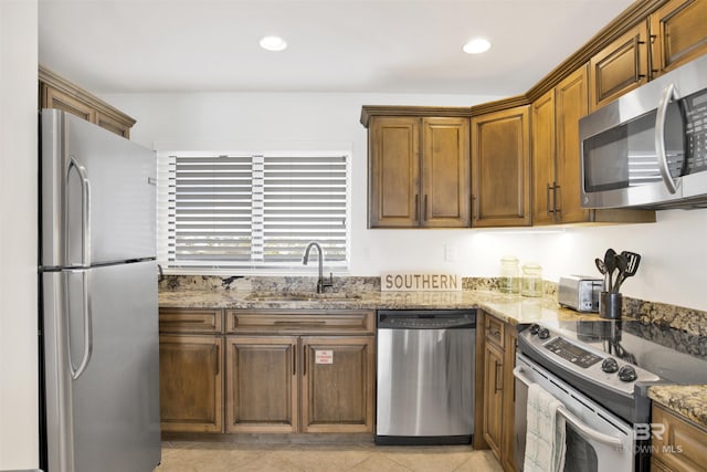 kitchen with appliances with stainless steel finishes, recessed lighting, a sink, and light stone countertops