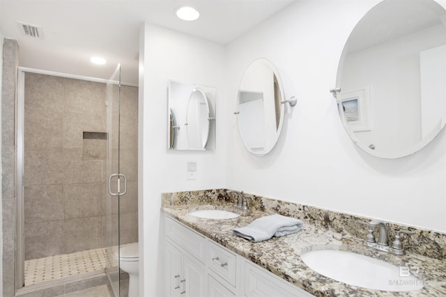 full bathroom with double vanity, a shower stall, visible vents, and a sink