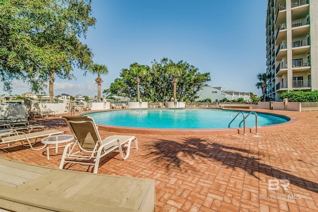 community pool with a patio area and fence