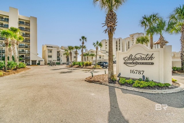 community sign with uncovered parking and a residential view