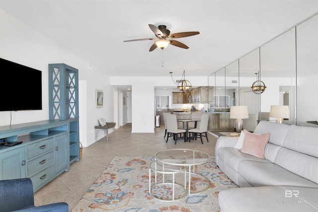 living area with light tile patterned flooring and ceiling fan with notable chandelier