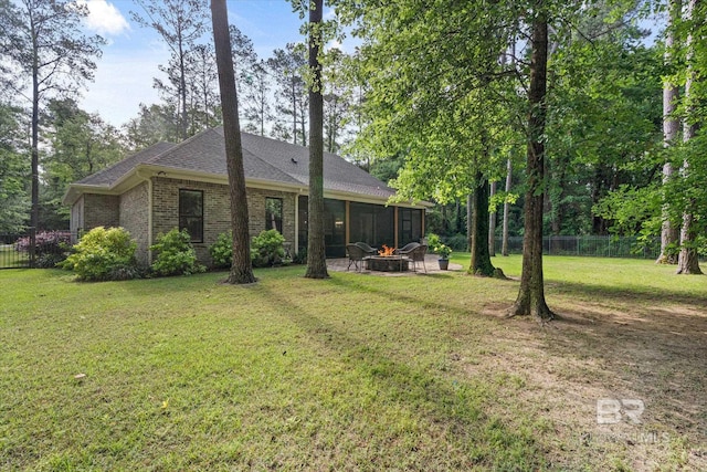 3250 Riviere Du Chien Rd, Mobile, AL 36693 - rear view of house featuring an outdoor fire pit, a sunroom, brick siding, and a shingled roof
