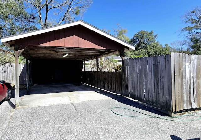 view of parking with a carport, fence, and aphalt driveway