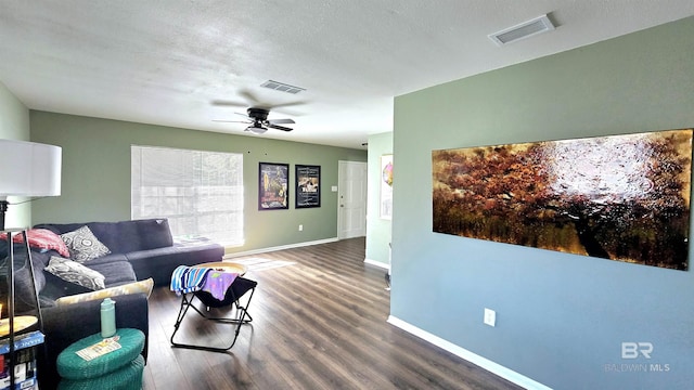 living room featuring dark wood-type flooring, visible vents, and baseboards